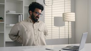 Arabian Indian business man sick male businessman employee working laptop feel ache pain hurt back